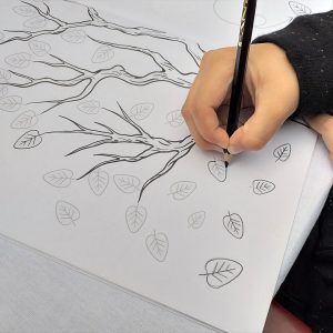 Dječak crta linije lišća na drvetuu